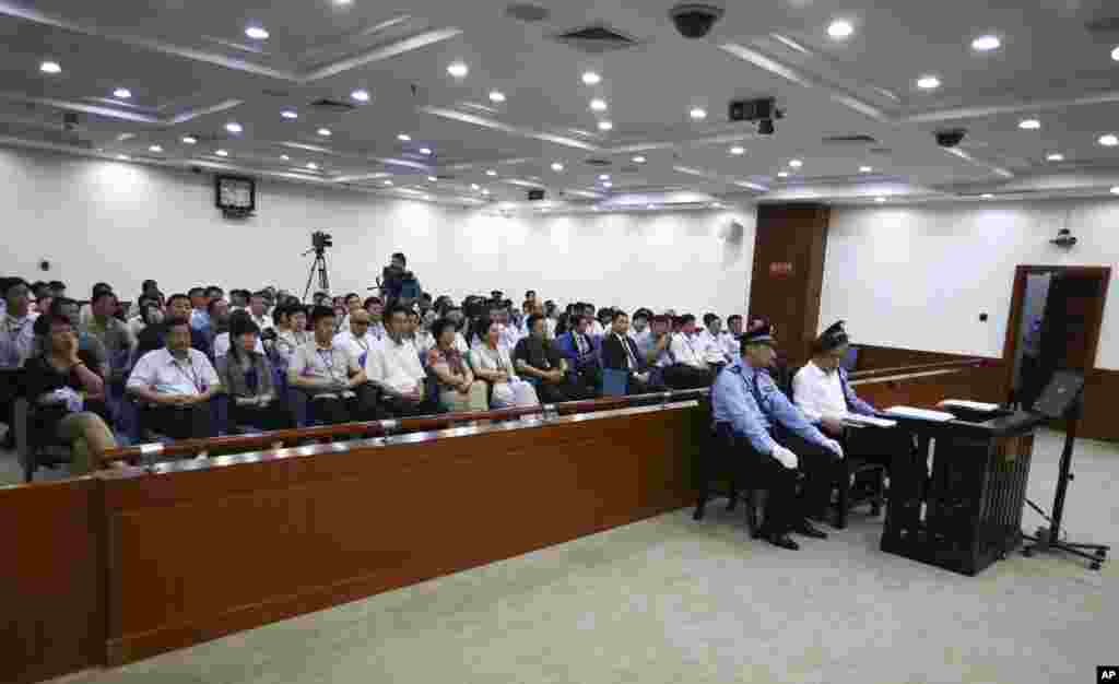 In this photo released by the Jinan Intermediate People's Court, disgraced politician Bo Xila is flanked by police officers during his trial at the court in eastern China's Shandong province, August 22, 2013.