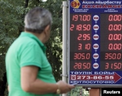 A man walks past a board showing currency exchange rates in Almaty, Kazakhstan, Aug. 20, 2015.