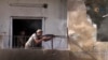 FILE - This frame grab from video released Aug. 3, 2017, and provided by Hawar News Agency, a Syrian Kurdish activist-run media group, shows a fighter from the US-backed Syrian Democratic Forces firing his weapon during clashes with Islamic State group. 