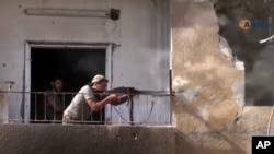 FILE - This frame grab from video released Aug. 3, 2017, and provided by Hawar News Agency, a Syrian Kurdish activist-run media group, shows a fighter from the U.S.-backed Syrian Democratic Forces firing his weapon during clashes with Islamic State group fighters in the northern city of Raqqa, Syria.