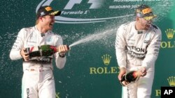 Pebalap Nico Rosberg (kiri) menyemprotkan sampanye ke teman satu timnya, Lewis Hamilton setelah memenangkan gelar GP Monaco Minggu (24/5).