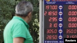 A man walks past a board showing currency exchange rates in Almaty, Kazakhstan, Aug. 20, 2015. 