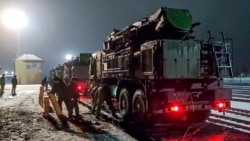 In this photo taken from video provided by the Russian Defense Ministry Press Service on Jan. 29, 2022, Russian military vehicles prepares to drive off a railway platforms after arrival in Belarus.
