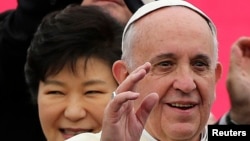 Pope Francis waves upon his arrival at Seoul Air Base, as South Korean President Park Geun-hye (L) smiles, in Seongnam, Aug. 14, 2014.