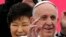 Pope Francis waves upon his arrival at Seoul Air Base, as South Korean President Park Geun-hye (L) smiles, in Seongnam, Aug. 14, 2014.