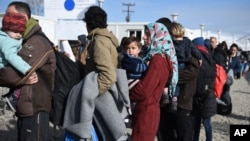 Refugees wait in line for their documents to be checked by the Greek police before they cross the borderline to Macedonia near the northern Greek village of Idomeni, on Sunday, Feb. 21, 2016. Macedonia has closed its southern border with Greece to Afghan migrants, allowing only Iraqis and Syrians, Greek police report. (AP Photo/Giannis Papanikos)