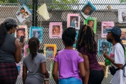 FILE - Melissa Brooks, from left, Jordan Brown, Jazmine Brooks, Shari Moore and and Laila Brooks, all of Baltimore, study photographs of Black people killed by police that cover a fence near the White House, Washington, Aug. 25, 2020.