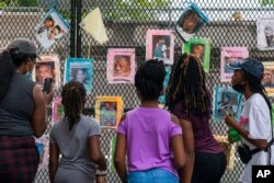 FILE - Melissa Brooks, from left, Jordan Brown, Jazmine Brooks, Shari Moore and and Laila Brooks, all of Baltimore, study photographs of Black people killed by police that cover a fence near the White House, Washington, Aug. 25, 2020.