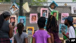 Melissa Brooks, from left, Jordan Brown, Jazmine Brooks, Shari Moore and and Laila Brooks, all of Baltimore, study photographs of Black people killed by police that cover a fence near the White House, Washington, Aug. 25, 2020.