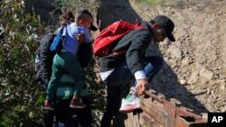 온두라스 출신 이민자들이 지난 16일 멕시코-샌디에이고 장벽을 넘고 있다. 