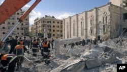 Syrian workers inspect the site of an explosion outside a military security building, one of two sites of bomb blasts in Syria's northern city of Aleppo, February 10, 2012.