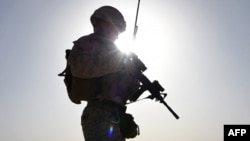 FILE - A U.S. Marine watches Afghan commandos take part in a combat training exercise at Shorab Military Camp in Lashkar Gah, Helmand province, Aug. 27, 2017.