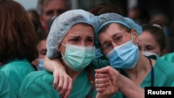 Health workers wearing protective face masks react during a tribute for their co-worker Esteban, a male nurse that died of the coronavirus disease, amid the coronavirus disease (COVID-19) outbreak, outside the Severo Ochoa Hospital in Leganes, Spain, Apri