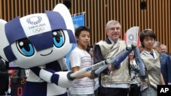 IOC President Thomas Bach poses for a photo with Japanese junior high school student Yui Hashimoto, right, and Yuto Tojima, second from left, and Miraitowa, mascot of Tokyo 2020 during a Olympic Games Tokyo 2020 One year to Go ceremony event in Tokyo, Wednesday, July 24, 2019. 