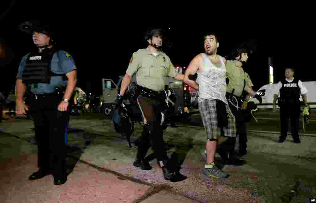 A man is lead away after being detained by police, Ferguson, Missouri, Aug. 18, 2014.