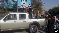 FILE - A Taliban fighter stands guard on a vehicle in Kunduz, north of Kabul, Afghanistan, Sept. 2015.