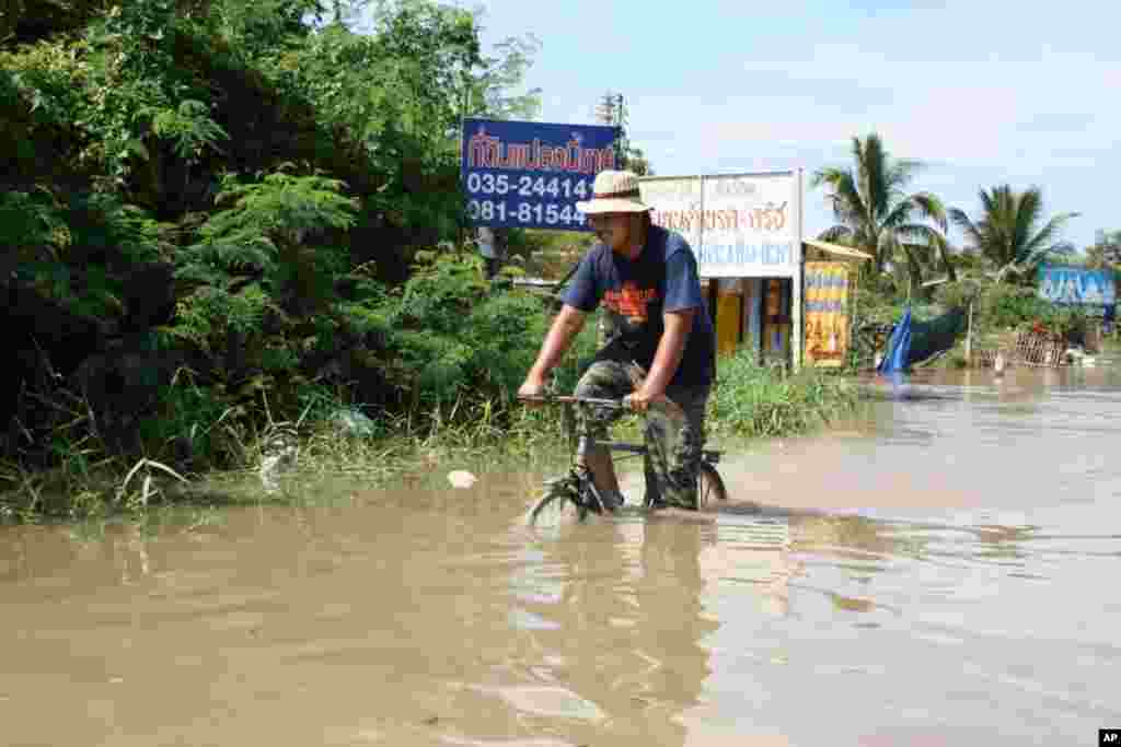Man bikes on a flooded road in Ayutthaya, October 6, 2011 (VOA - D. Schearf)