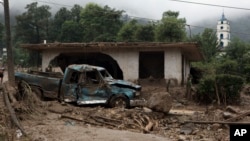 FILE - A pickup lies destroyed next to a house damaged by a mudslide in Xaltepec, on the mountainous north of Puebla state, Mexico, Aug. 7, 2016. The death toll from the remnants of Hurricane Earl grew to more than 30 in Mexico as a new tropical storm formed off the country's Pacific Coast.
