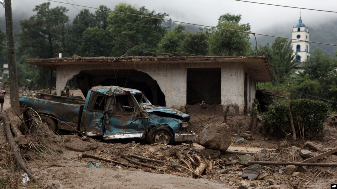 FILE - A pickup lies destroyed next to a house damaged by a mudslide in Xaltepec, on the mountainous north of Puebla state, Mexico, Aug. 7, 2016. The death toll from the remnants of Hurricane Earl grew to more than 30 in Mexico as a new tropical storm formed off the country's Pacific Coast.
