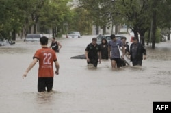 Orang-orang berjalan di jalan yang banjir setelah badai dahsyat melanda kota Bahia Blanca, 600 km selatan ibu kota Argentina, pada 7 Maret 2025. (Foto: AFP)