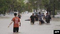 Personas caminan por una calle inundada después de que una poderosa tormenta azotara la ciudad de Bahía Blanca, a 600 kilómetros al sur de la capital de Argentina, el 7 de marzo de 2025.