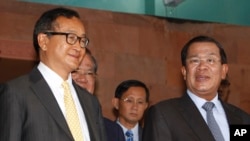 FILE PHOTO - Cambodian Prime Minister Hun Sen, right, talks with the main Opposition Party leader Sam Rainsy, left, of Cambodia National Rescue Party, after their meeting in Senate headquarters in Phnom Penh, Cambodia, Tuesday, July 22, 2012. (AP Photo/Heng Sinith)