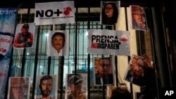 FILE - A woman posts photos of murdered journalists during a national protest against the murder of journalists Lourdes Maldonado and freelance photojournalist Margarito Martínez, in Mexico City, Jan. 25, 2022.