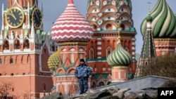 Una persona de seguridad está de guardia en el parque Zaryadye, con la torre Spasskaya del Kremlin y la Catedral de San Basilio vistas al fondo, en el centro de Moscú el 24 de marzo de 2020. 