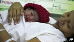 FILE - Danica Camacho is cuddled by her mother as they are wheeled out of the delivery room of the Government's Fabella Hospital moments after she was born October 31, 2011, in the Philippines.