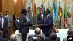 FILE - In this image made from video, South Sudan's President Salva Kiir, center left, and rebel leader Riek Machar, center right, exchange the signed documents in Addis Ababa, Ethiopia, May 9, 2014. 