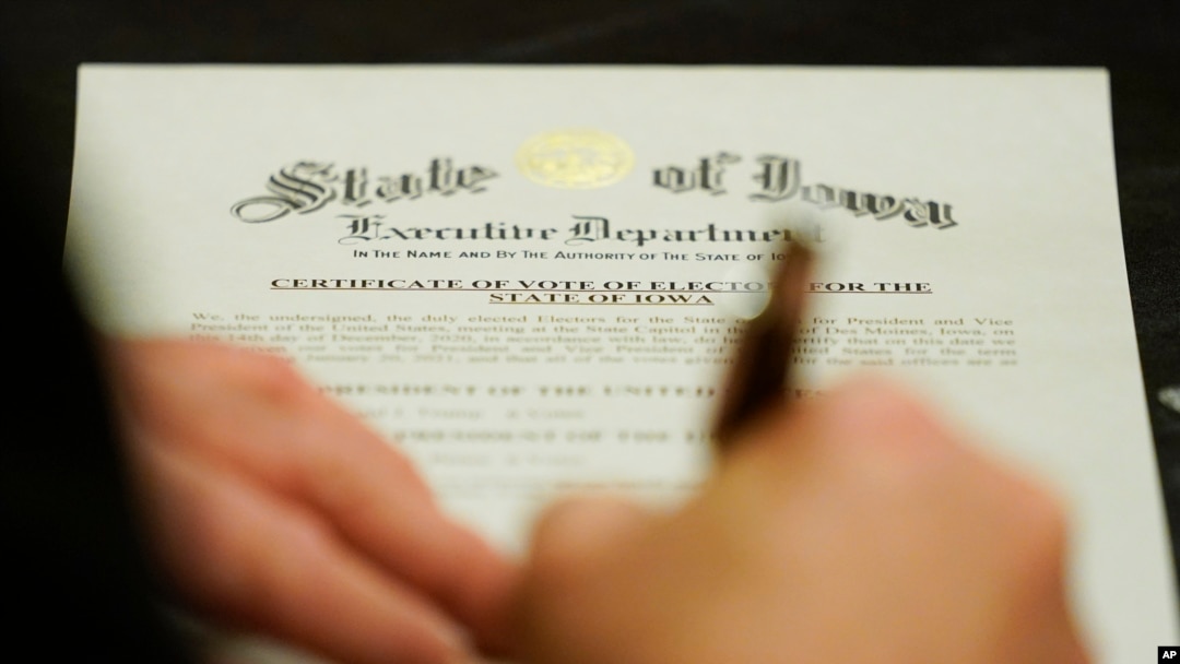 Seorang anggota Electoral College menandatangani Sertifikasi Pemungutan Suara Elektor untuk Negara Bagian Iowa, Senin, 14 Desember 2020. (AP Photo/Charlie Neibergall)