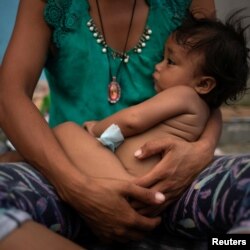 Estephanie, a one year old migrant girl from Honduras, is held by her mother while resting amid thousands from Central America en route to the United States, in Huixtla, Mexico, Oct. 23, 2018.