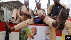 Des enfants assis sur un mur sur lequel est affiché un poster du président sortant de la Côte d'Ivoire, Alassane Ouattara, le 21 octobre 2015. (AP Photo/Schalk van Zuydam)