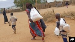 A newly arrived Somali family carry their supply of aid outside Dadaab, Eastern Kenya, Aug. 5, 2011. (AP)