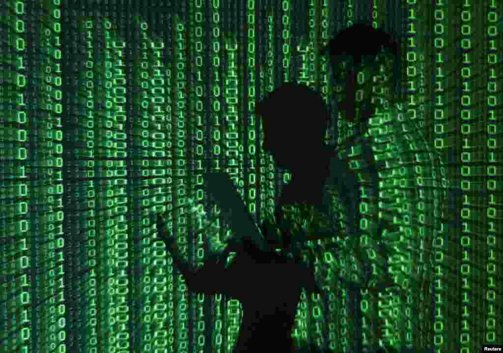 An illustration shows a projection of binary code on a man holding a laptop computer in an office in Warsaw, Poland.