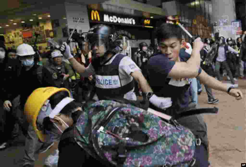 Police officers beat up protesters as they try to disperse them outside government headquarters in Hong Kong Monday, Dec. 1, 2014.