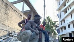 Workers look on at the site of the building collapse in Ikoyi, Lagos, Nigeria, Nov. 1, 2021. 