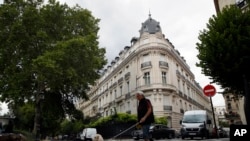 FILE - A man walks his dog next to an apartment building owned by Jeffrey Epstein in the 16th district in Paris, Aug. 13, 2019. 