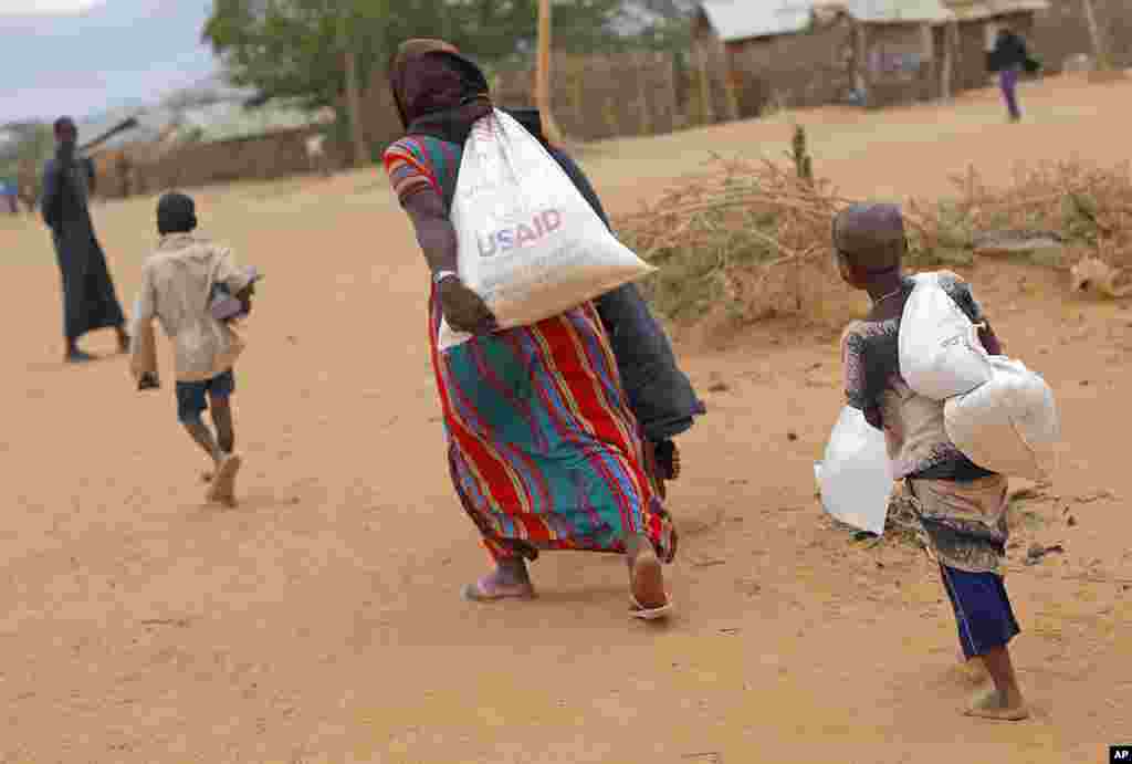A newly arrived Somali family carry their supply of aid outside Dadaab, Eastern Kenya, 100 kms (60 miles) from the Somali border, Aug. 5, 2011. (AP)