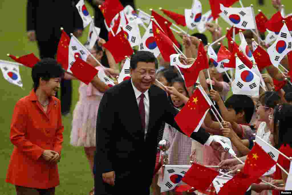 Chinese President Xi Jinping and South Korean President Park Geun-hye greet children waving the two countries' national flags during a welcoming ceremony at the presidential Blue House in Seoul, July 3, 2014. 