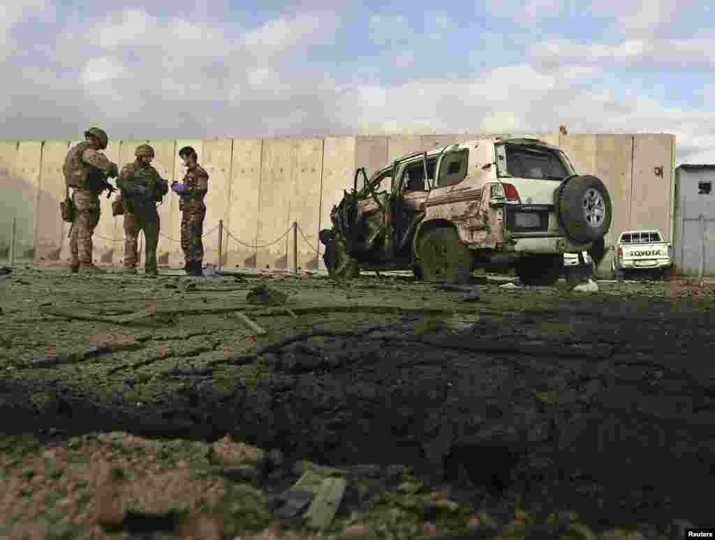 NATO troops investigate at the site of a suicide attack in Kabul, October 13, 2014.