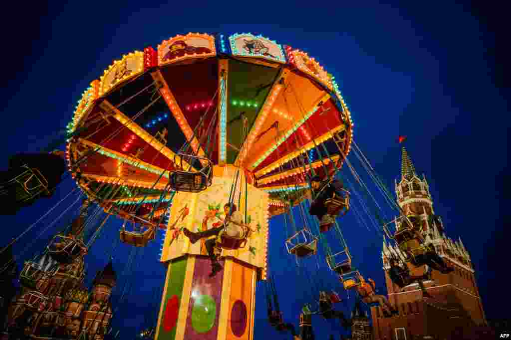 People ride a merry-go-round at the Christmas Market at the Red Square in Moscow, as the Kremlin&#39;s Spasskaya Tower is seen in the background, Dec. 16, 2019.