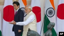 Indian Prime Minister Narendra Modi, right, shows the way to his Japanese counterpart Shinzo Abe as they arrive for their meeting, in New Delhi, India, Dec. 12, 2015. 