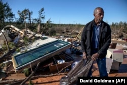 In this March 5, 2019 file photo, Richard Tate retrieves personal items from what's left of his home where he survived a tornado with his wife in Beauregard, Alabama.