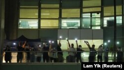 Staff light their phone flashlights and wave to supporters at the headquarters of the Apple Daily newspaper, and its publisher Next Digital, after the announcement that it will print its last edition, in Hong Kong, China June 23, 2021. (REUTERS/Lam Yik)
