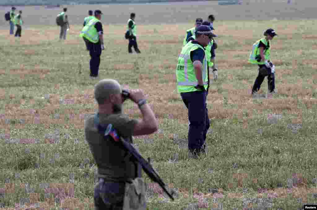 A pro-Russian separatist looks through binoculars as Dutch and Australian forensic experts continue recovery work at the site of the downed Malaysian airliner MH17 near the village of Rozsypne, in the Donetsk region, Aug. 4, 2014.