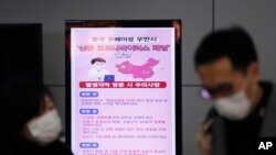 A poster warning about coronavirus is seen as passengers wear masks in a departure lobby at Incheon International Airport in Incheon, South Korea, Jan. 27, 2020. The U.S. issued a travel warning Thursday urging Americans not to travel to China.