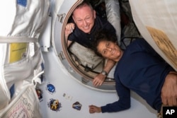 FILE - In this photo provided by NASA, astronauts Butch Wilmore, left, and Suni Williams pose for a portrait inside the vestibule between the forward port on the International Space Station's Harmony module and Boeing's Starliner spacecraft on June 13, 2024.