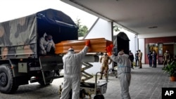 FILE - Coffins arriving from the Bergamo area, where the coronavirus infections caused many victims, are being unloaded from a military truck that transported them in the cemetery of Cinisello Balsamo, near Milan in Northern Italy, March 27, 2020.
