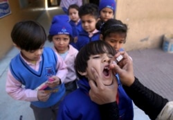 FILE - A health worker gives a polio vaccine to a child at a school in Lahore, Pakistan, Feb. 17, 2020.